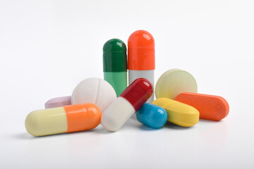 Various colorful pills and capsules on white background, various medicines, vitamins and supplements in healthcare and pharmacy concept.
