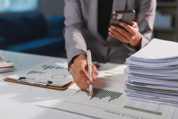 Businesswoman analyzing financial data on paper and smartphone