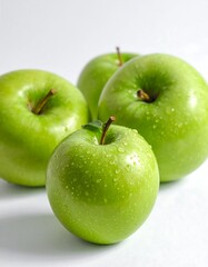 Four vibrant green fruits with water droplets against a white background