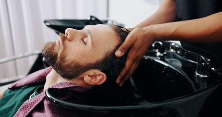 Hands, man and washing hair at barbershop with hygiene, basin and grooming services at salon. People, shampoo and conditioner for growth, cleaning and benefits with customer experience at store