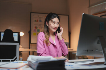 Young businesswoman talking on smartphone working late in office