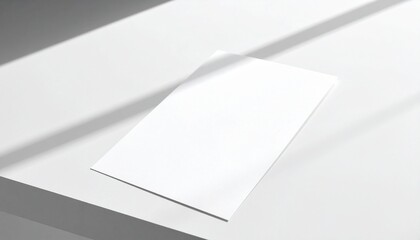 Blank white paper mockup casting a shadow on a white surface under light