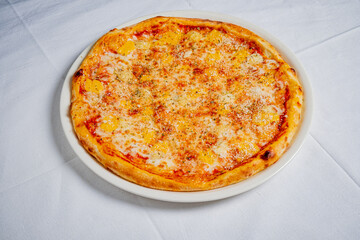Freshly baked pizza showcases a golden pineapple topping on a white tablecloth