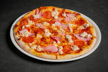 A mouthwatering pizza topped with ham, pepperoni, and creamy dollops of cheese waits to be enjoyed
