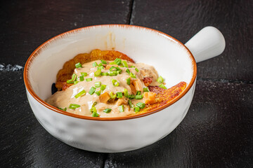 Delightful dish of golden plantains smothered in creamy sauce, garnished with fresh herbs
