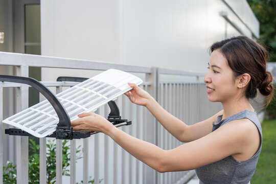 Woman Maintenance cleaning and replacing dirty air filter of air conditioning unit.