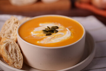 creamy pumpkin soup garnished with seeds and served with crusty bread, creating a warm and inviting autumnal dining scene with soft textures and a harmonious color palette, appetizer, presentation