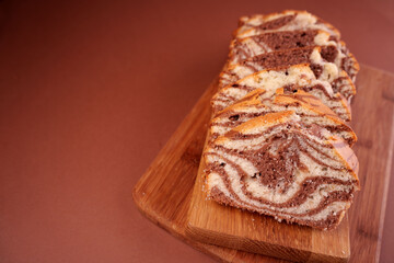 close-up of marble cake slices arranged on wooden board against a warm brown background with rich swirls of chocolate and vanilla highlighted in soft light, handcrafted, savory, homely, satisfying