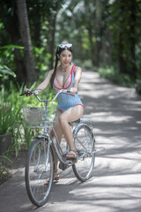 Woman in swimsuit with bicycle, tropical garden background.