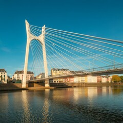 Obraz premium Wideangle view of a modern cablestayed bridge spanning a river, featuring a tall white tower with multiple cables supporting the deck, under a clear blue sky during daytime