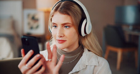 Woman, headphones and phone with music in home, scroll and choice for song on web in living room. Person, smartphone and listen with audio on mobile app, streaming subscription or relax at apartment