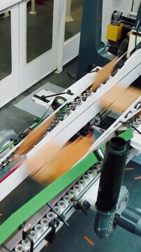 Speedy conveyor with sensors for efficient cardboard handling, Rapid industrial conveyor system equipped with sensors and guiding rollers for optimized cardboard processing and alignment