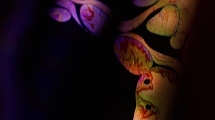 Fluorescent fluid. Ink blob blur. Black drop blend in water gasoline surface. Purple orange color pigment glow abstract background free space.