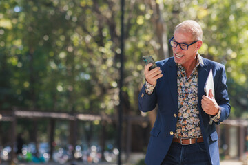Happy mature man receiving good news on phone