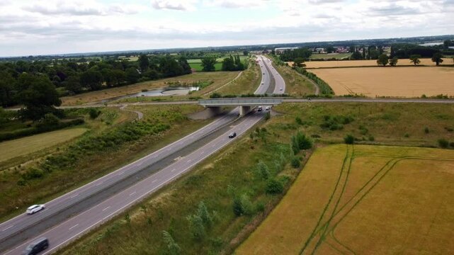 Aerial footage over Norfolks NDR. Footage slowly lowers whilst vehicle drive along the Broadland Northway with middle road bridge,