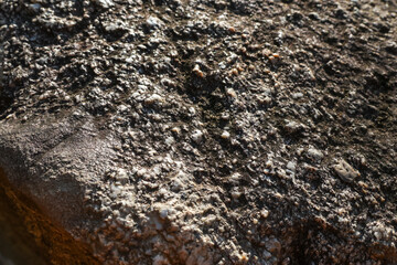 Rough stone surface shows natural granite rock texture. Closeup detail of geology pattern, with brown and grey mineral background creating solid and earthy feel