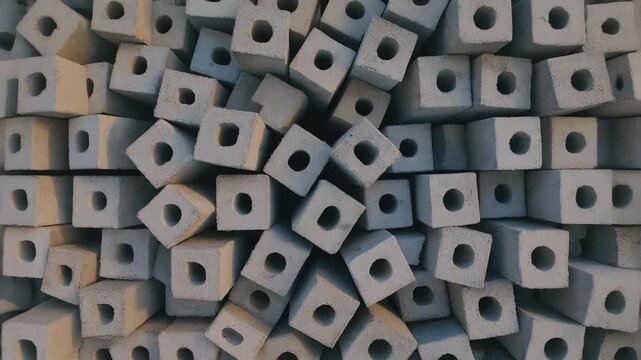 Abstract pattern of stacked concrete blocks with square holes, showcasing industrial texture and geometric design