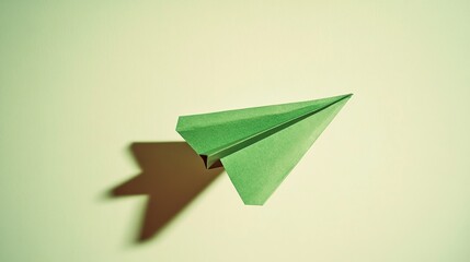 Bright green paper airplane soaring diagonally across a pale mint-green background with a shadow