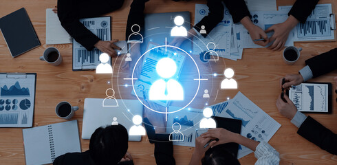 A group of business professionals engaged in a strategy session, analyzing data and collaborating on ideas, with digital networking graphics enhancing their discussion. Trope