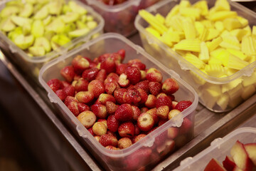 Colorful assortment of fresh fruit ingredients prepared in containers. Red berries and yellow jackfruit at food market stall, vibrant and healthy choice for snack