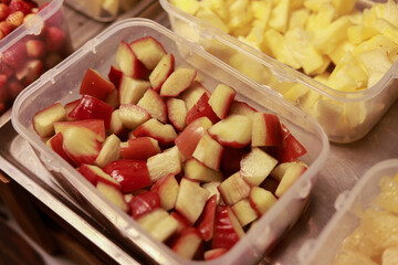 Close up view of fresh chopped red apple and pineapple in plastic containers. Healthy food preparation for nutritious snack or meal prep, ready for fresh diet