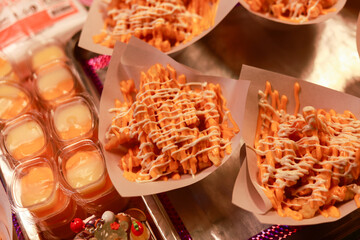 Appetizing street food, close up of delicious waffle fry with sauce topping at food stall. This fast food popular snack available for takeaway at night market
