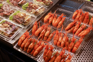Cooked red shrimp and fresh seafood on display at an appetizing market stall. Delicious prawn and other street food for sale, ready to eat for tasty meal or snack