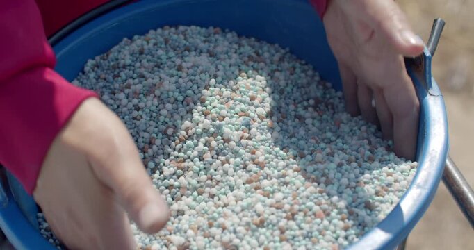Two types of fertilizer are mixed together in a container before application, ensuring balanced nutrients for crop growth.