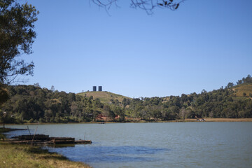 Serene lake on beautiful sunny day. Green hill and forest surround water under clear blue sky. peaceful landscape in nature offering tranquil feeling
