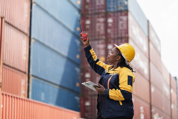 Portrait African woman logistics workers use notebook computer and walkie talkie checking container	