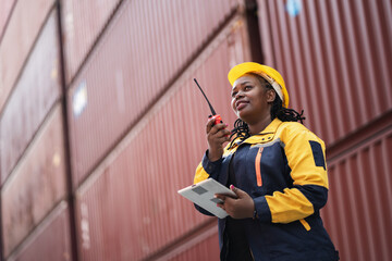 Portrait African woman logistics workers use notebook computer and walkie talkie checking container	