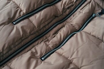 Close-up image showing the detail of a black zipper pull on beige canvas fabric