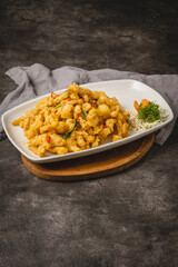 Golden crispy chicken or seafood dish with chili and herbs, served on a white plate with a side garnish.