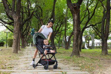 Obraz premium Mum pushing baby stroller while walking at park