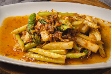 A close-up shot of a delicious stir-fried dish with asparagus and meat in a savory sauce, served on a white rectangular plate.