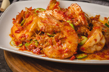 Spicy chili shrimp with petai beans on a white plate, a traditional Southeast Asian dish.