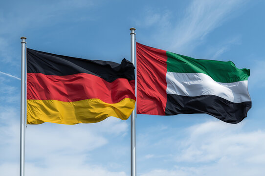Flags of Germany and the United Arab Emirates waving side by side against a blue sky, symbolizing bilateral relations, international trade, and diplomacy.
