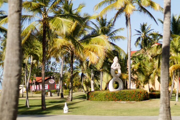 A beautiful seaside resort with palm trees, colorful buildings, and artistic statues on a sunny summer day. Vacation season in the Caribbean. Hotel in Punta Cana, Dominican Republic, July 22, 2025