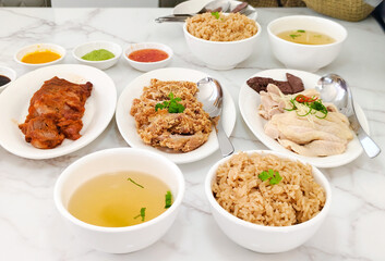Steamed rice topped with chicken, deep-fried chicken, soup, and red pork. Thai delicious street food. High protein nutrition. Wide angle.