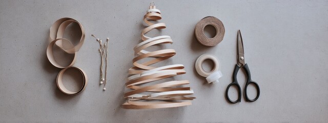 Creative holiday workspace with paper tree, ribbons and scissors in soft daylight and neutral tones.  banner 
