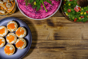 Tartlets with red caviar and festive salads on a wooden table. Festive food