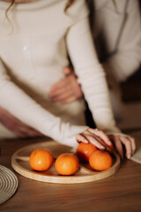 A cozy moment with mandarins on a plate in the foreground and a couple embracing in the background