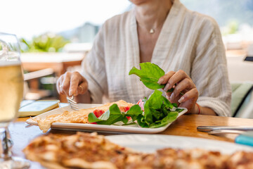 Woman is seated at a table with plate of salad and glass of drink