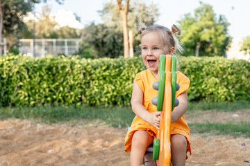 girl smiles joyfully while playing on colorful playground equipment