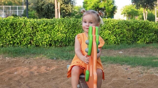 girl smiles joyfully while playing on colorful playground equipment