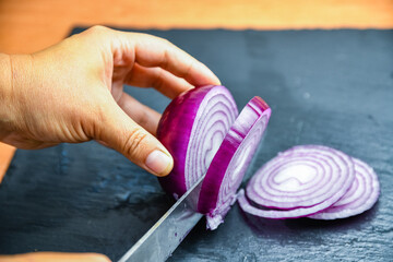 Woman cutting red onion on cutting board