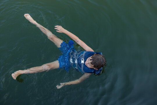 boy in lifejacket floating on calm lake