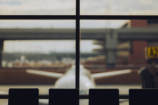 Tail of a parked airplane framed through the terminal window.