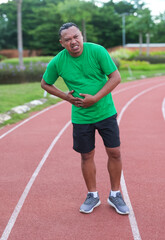 Athletic man on running track has side cramps during workout
