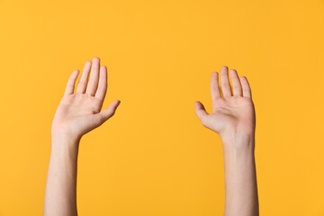 Hands raised against a bright yellow background, capturing a simple gesture of attention and openness. Minimalist concept suitable for communication, collaboration, safety, energy, or celebration in